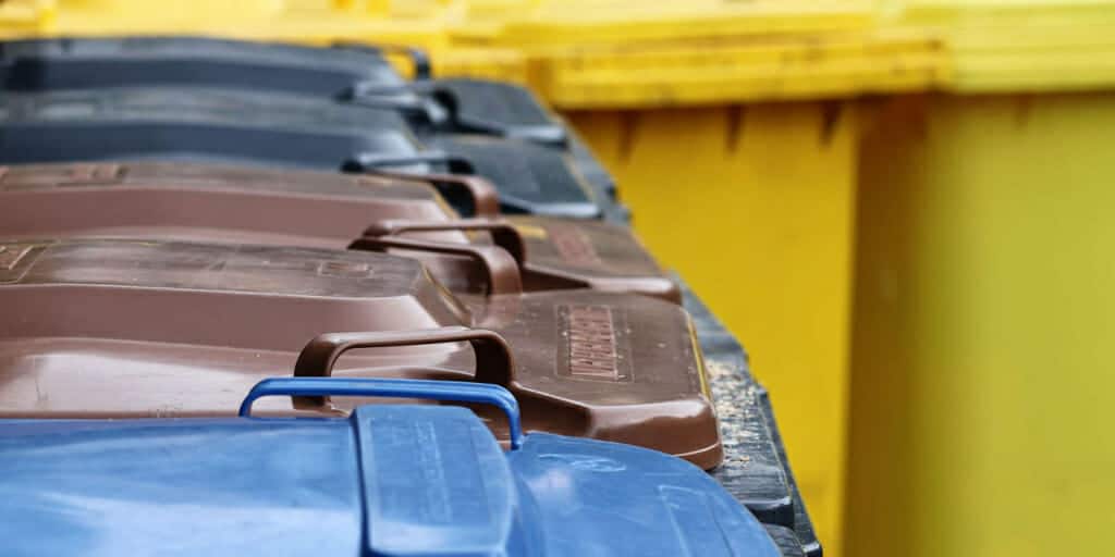 Verschiedenfarbige Mülltonnen in einer Reihe aufgestellt