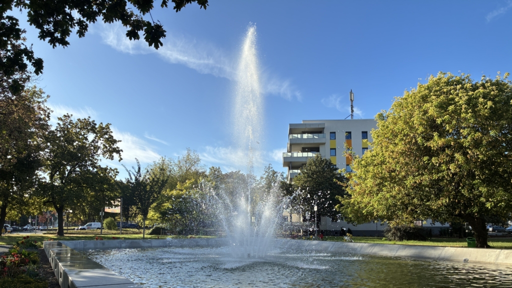 Sprudelnde Wasserfontäne des erneuerten Lions-Brunnens am Breiten Weg in Halberstadt vor modernem Gebäude